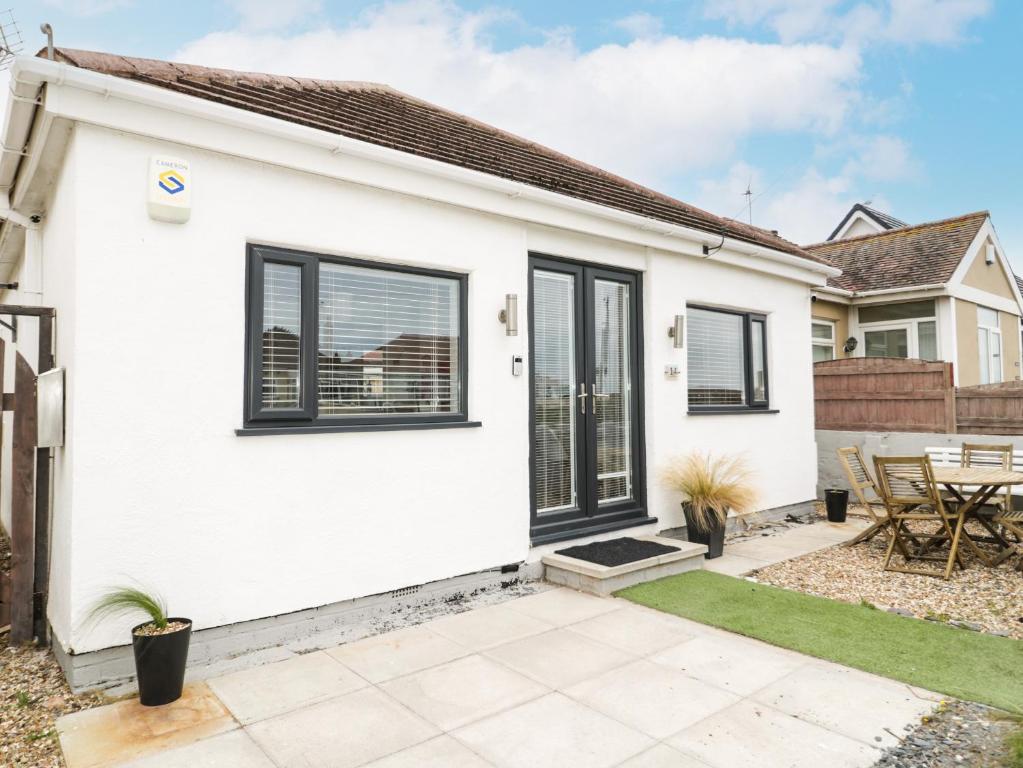 a white house with black windows and a patio at Cove House in Rhyl