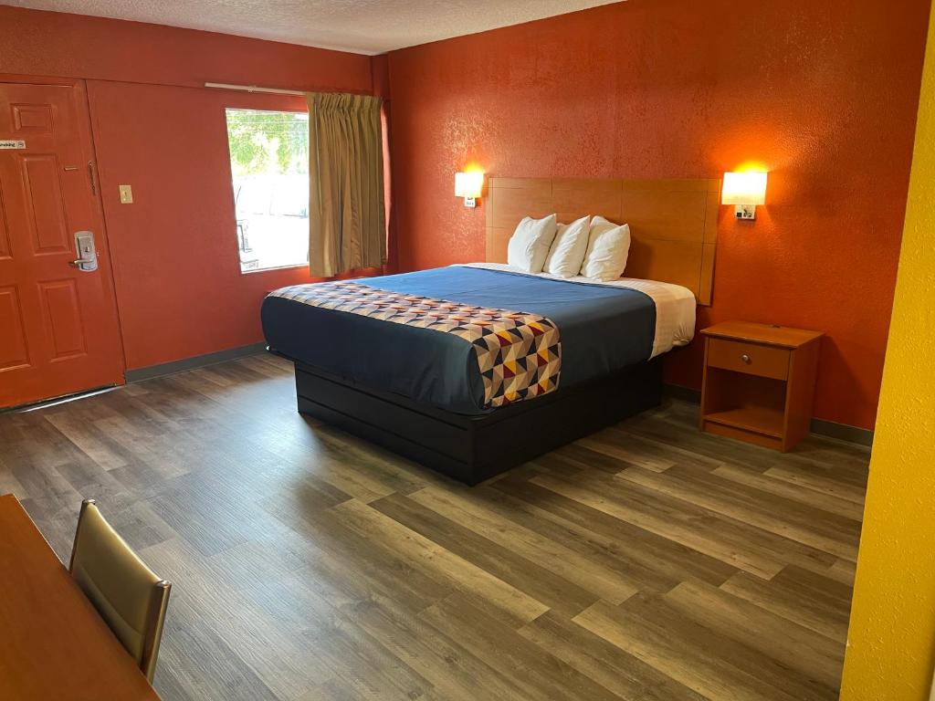 Habitación de hotel con cama con paredes de color naranja en Economy Inn Hot Springs, en Hot Springs