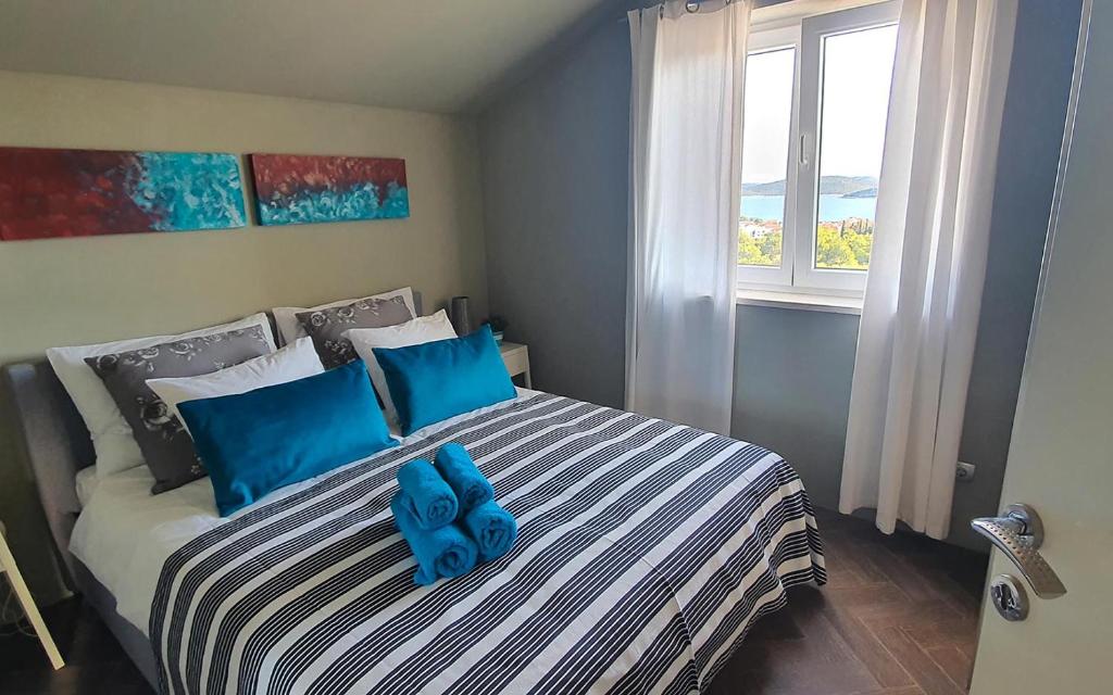 a bedroom with a bed with blue pillows and a window at Apartments Macaklin in Vodice