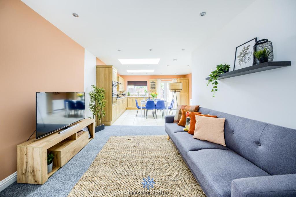 sala de estar con sofá azul y TV en Coventry Large Stylish 4 Bedroom House, Sleeps 8, Private Parking, by EMPOWER HOMES en Coventry
