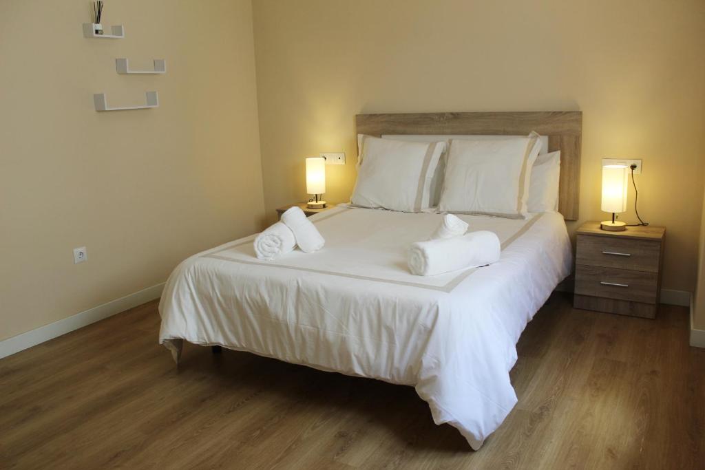 Apartamento Ronda Naranja by CasaTuristica في روندا: غرفة نوم بسرير ابيض كبير ومصباحين