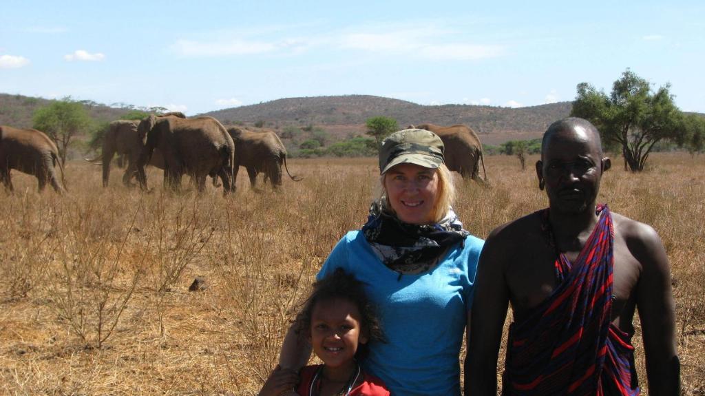 a man and a woman standing in front of a herd of elephants at Maasai Simba Camp in Amboseli