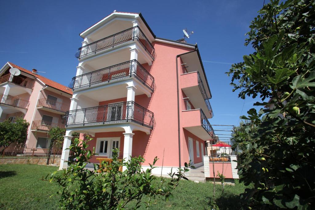 un edificio rosa con balcones en un lateral en Apartments Villa Dalmazia, en Trogir
