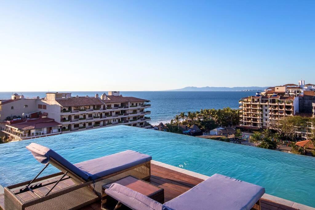 a swimming pool with two lounge chairs and the ocean at Nayri Life 509 in Puerto Vallarta