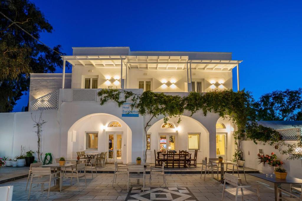 un bâtiment blanc avec des tables et des chaises devant lui dans l'établissement Hotel Eucalyptus, à Mesariá