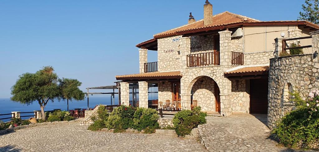 a large stone building with a porch and a tree at Nireas : Stone Villa in Zakynthos Town