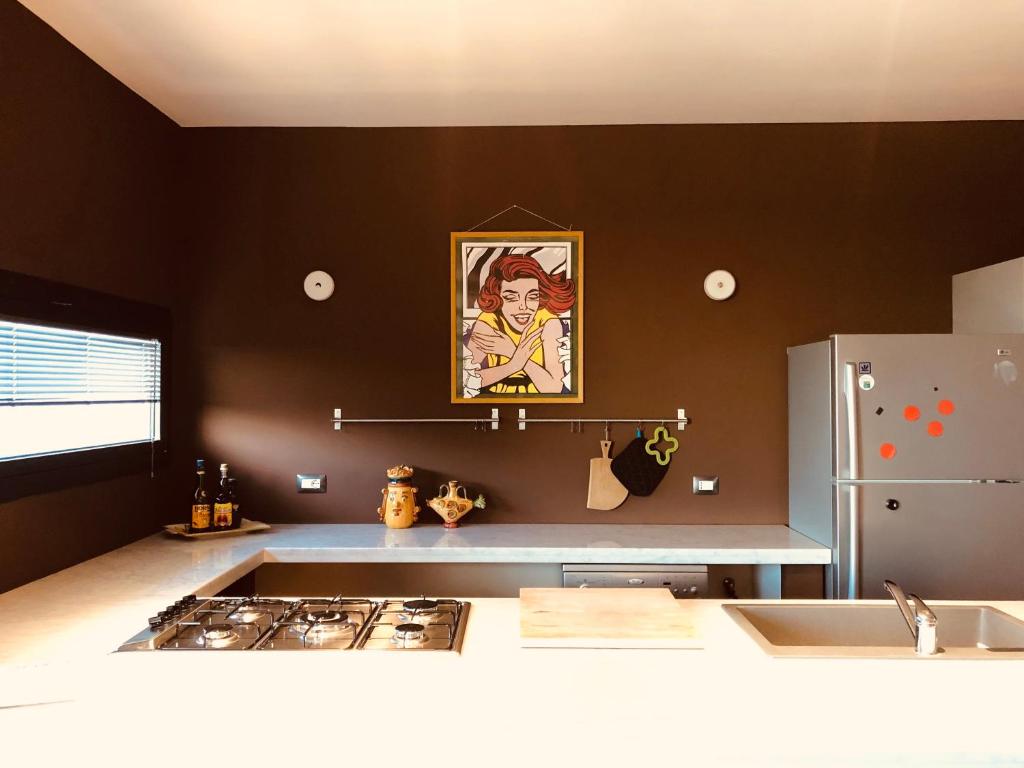 a kitchen with a painting of a woman on the wall at oPENhouse - loft - casa al mare in Pizzo