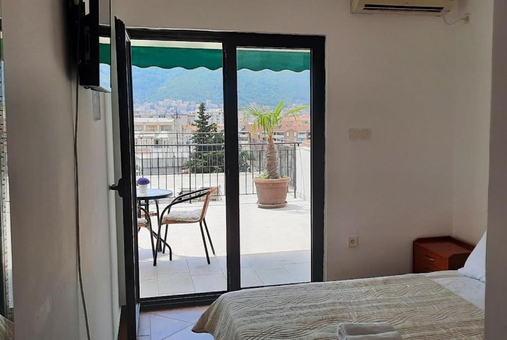 Schlafzimmer mit einer Tür, die auf eine Terrasse mit einem Tisch führt in der Unterkunft Villa Lutovac Budva in Budva