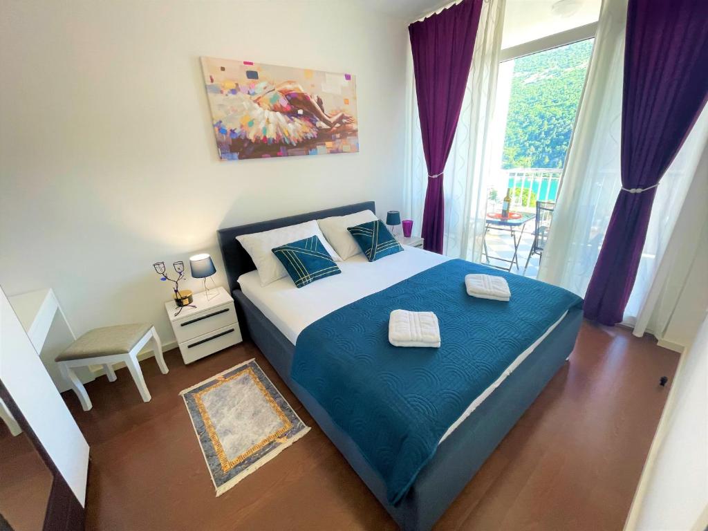 um quarto com uma cama com lençóis azuis e uma janela em Bonki apartment private free parking em Mokosica