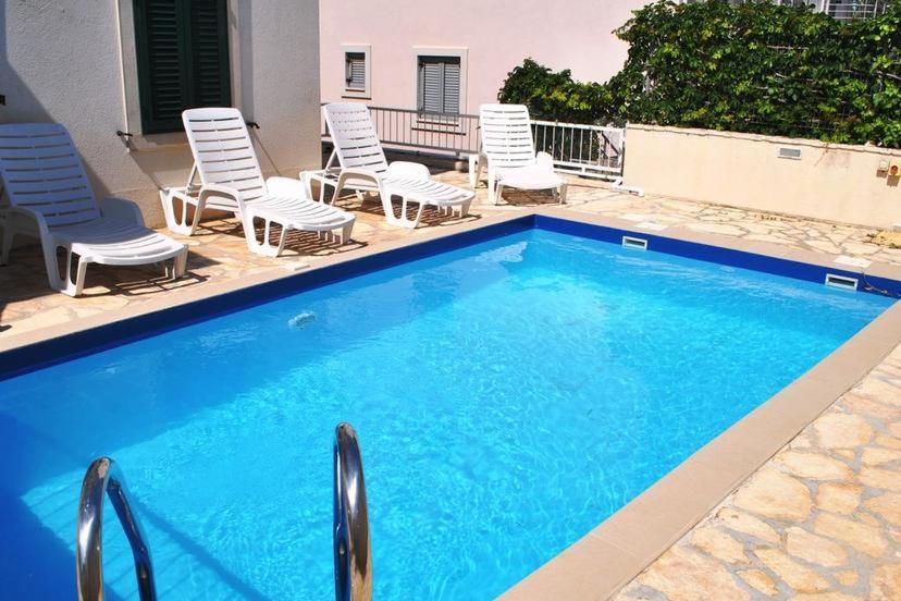 a swimming pool with chairs and a group at Appartamento Daisy con vista mare e piscina in Supetar