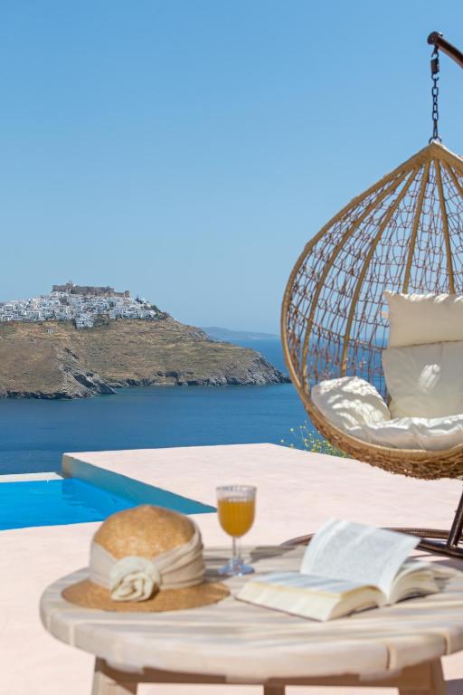 a table with a book and a glass of orange juice at Nisides Suites in Livadi Astypalaias