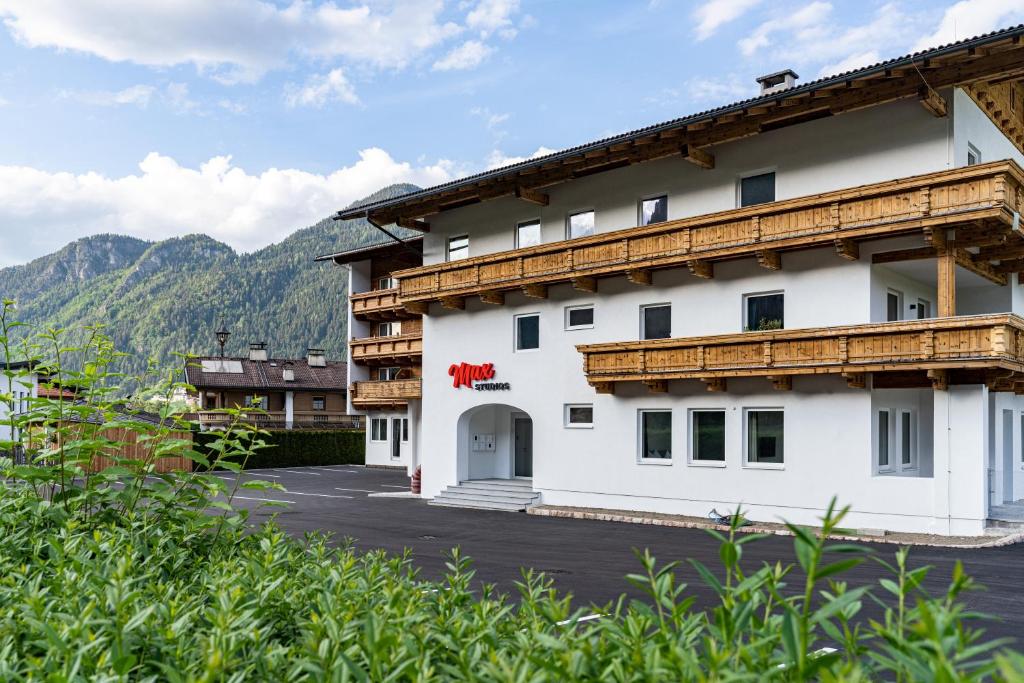 un grande edificio bianco con montagne sullo sfondo di Max Studios & Apartments - Zillertal a Schlitters