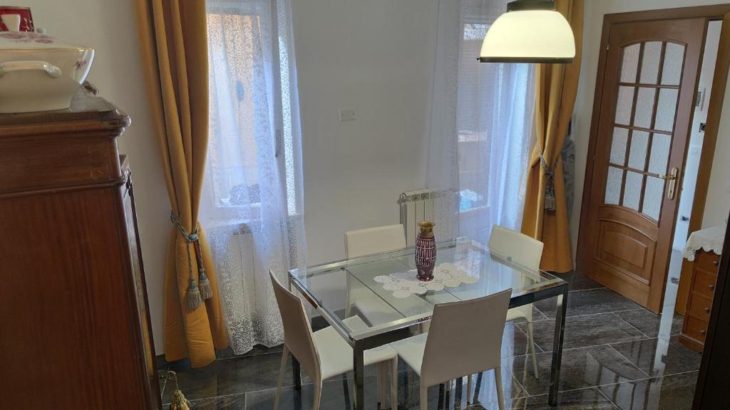 mesa de comedor de cristal con sillas blancas y lámpara en La Badia del Cavaliere 1, en Roma