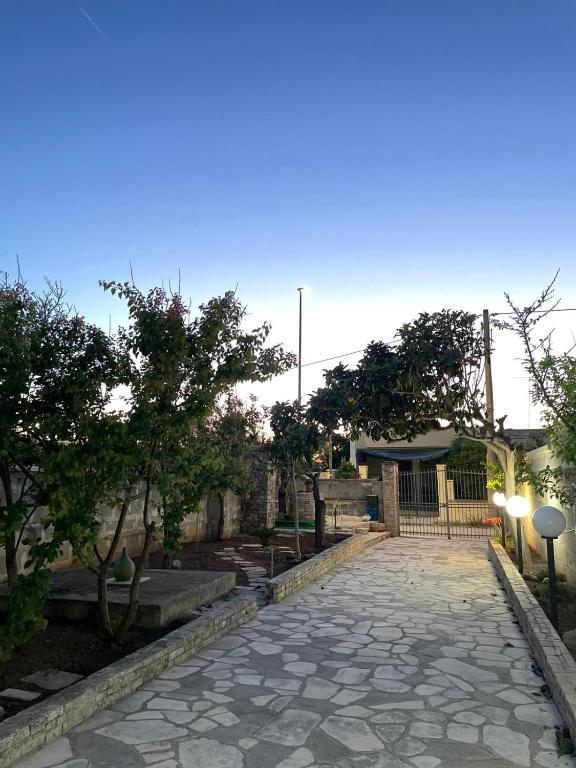 a stone walkway in front of a building with trees at Casa Vacanze Linuccio in Casalabate