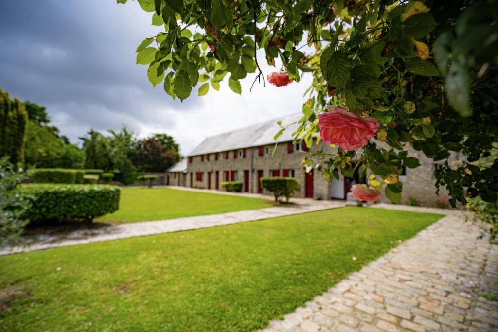 a building with a green yard and a building with roses at Domaine Malar in Guillerval