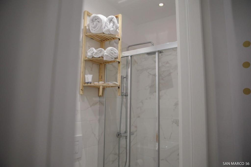 a bathroom with a shower with towels on a shelf at San marco 56 in Bari