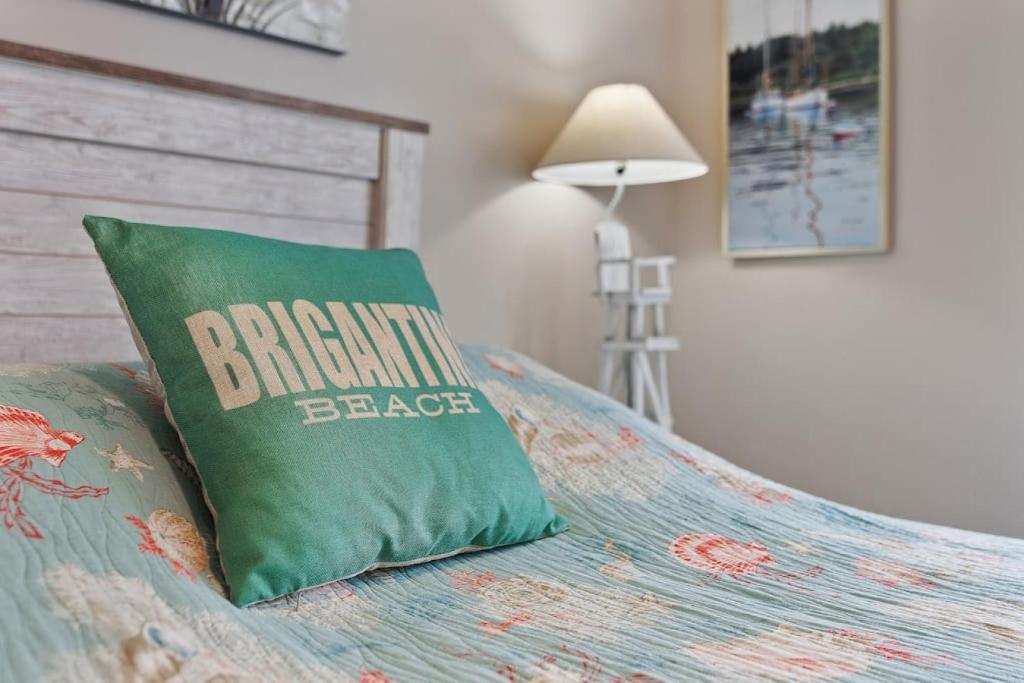 a bed with a green pillow on top of it at Radiant Beach Block Condo Parking Patio in Brigantine