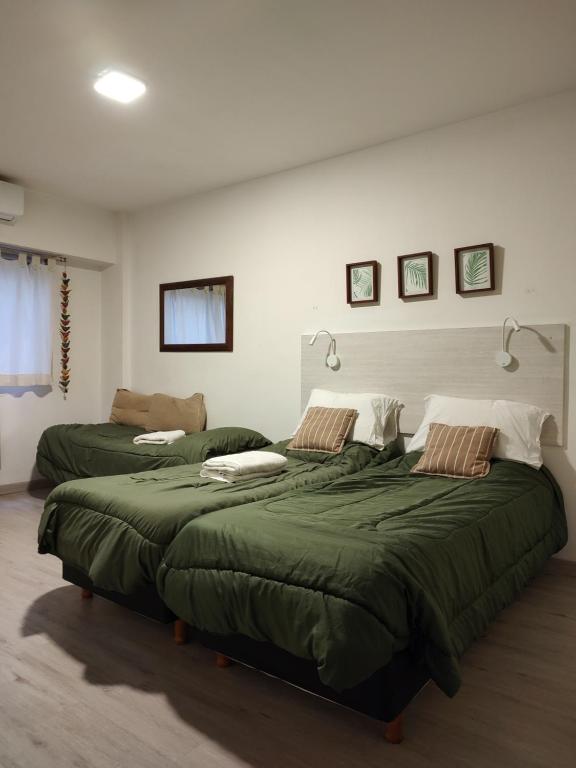 2 camas en una habitación con edredones verdes en Porteño 7 Hospital Italiano en Buenos Aires