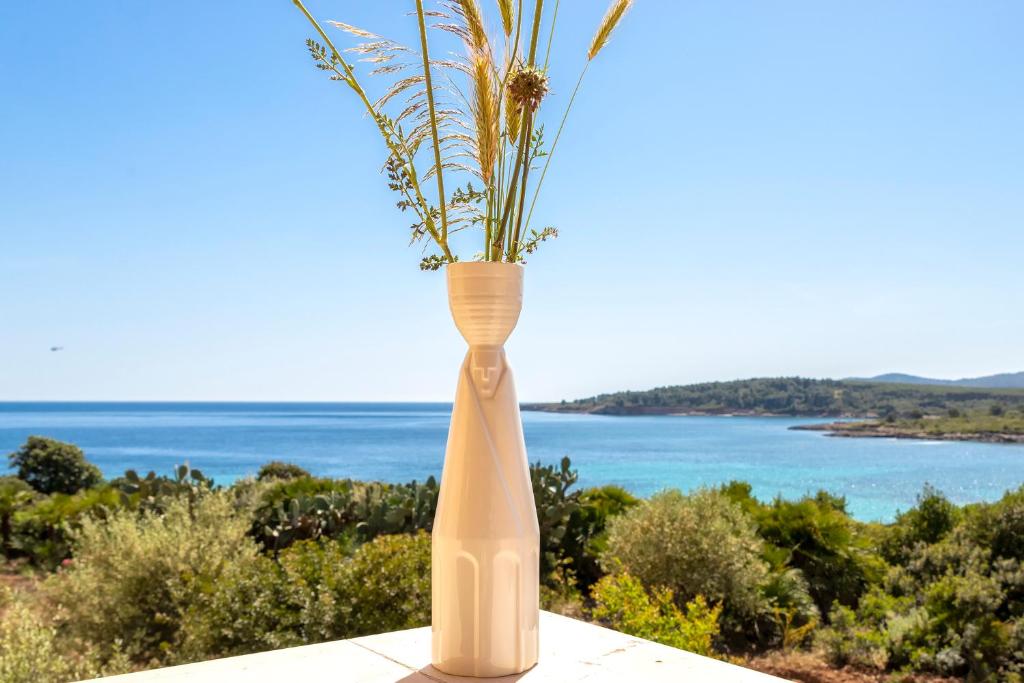 un grande vaso bianco con una pianta di Dea Fertilia. Casa indipendente con vista mare. a Fertilia