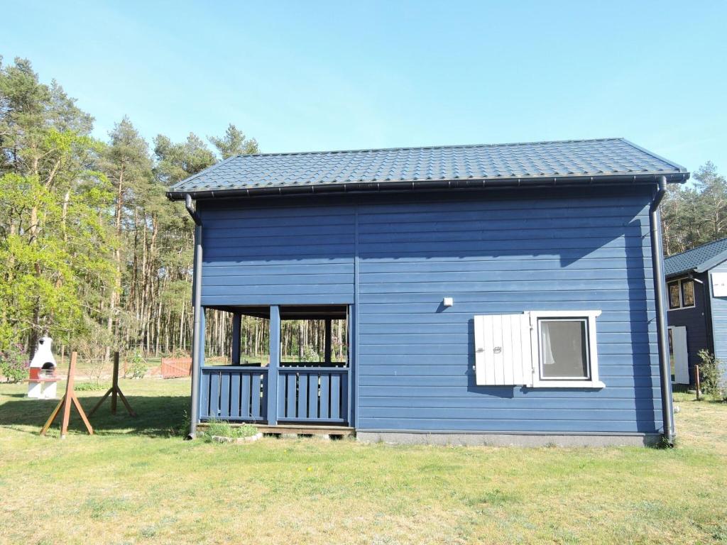 a blue shed in a yard with a person in the background at holiday home, Nowe Warpno in Nowe Warpno