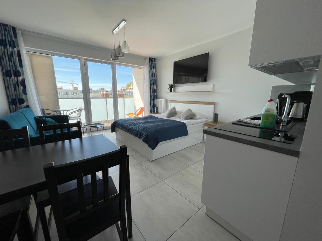 a kitchen and a living room with a bed and a table at Plaza Luxury Apartments in Kołobrzeg