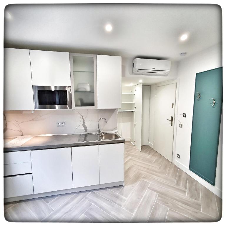 a kitchen with white cabinets and a sink at Le Vallaya Suites & Spa in Menton