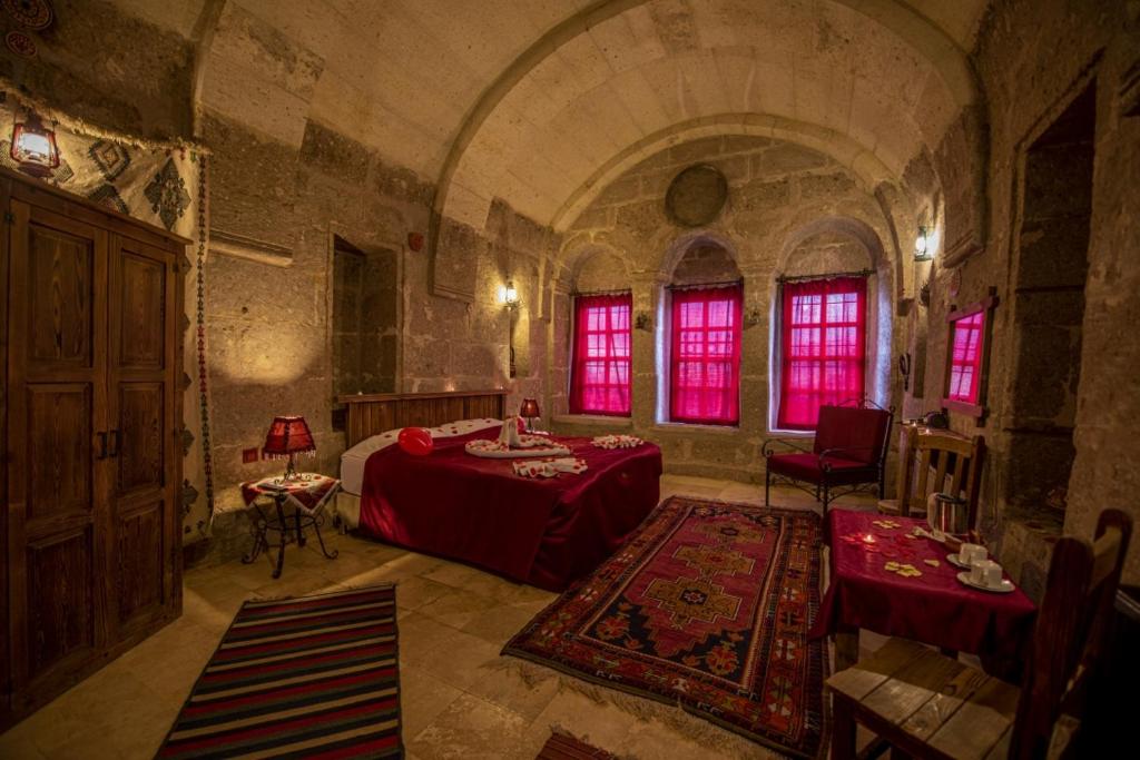 1 dormitorio con 1 cama y 1 mesa en una habitación en Cappadocia Antique Gelveri Cave Hotel, en Guzelyurt