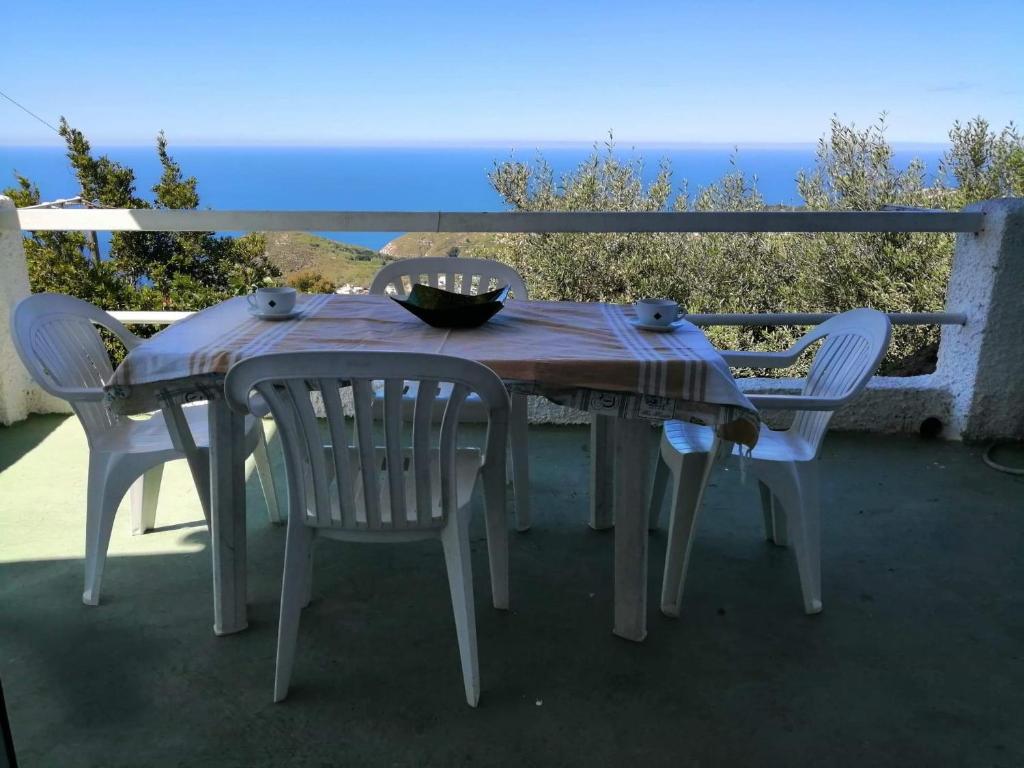 a table and chairs with a table and a view of the ocean at Appartamento di villa gesualda in Serrara Fontana