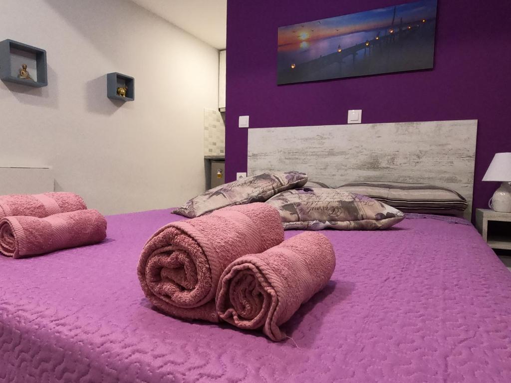 Una cama morada con toallas encima. en MEMORIA, en Corfú
