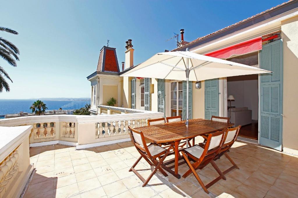 una mesa de madera y sillas con sombrilla en una casa en Magnifique appartement d'époque avec Vue Mer 4 personnes avec terrasse Le Port Nice en Niza