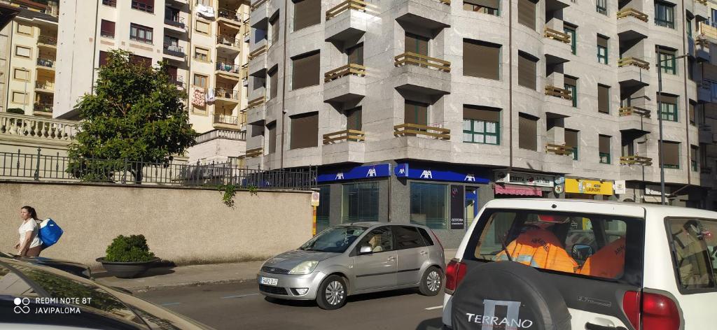 dos coches estacionados en una calle de la ciudad con edificios en Apartamentos xistra, en Cangas del Narcea