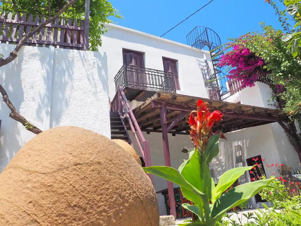 biały budynek z balkonem i kwiatem w obiekcie Cycladic House in Skiros w mieście Skiros