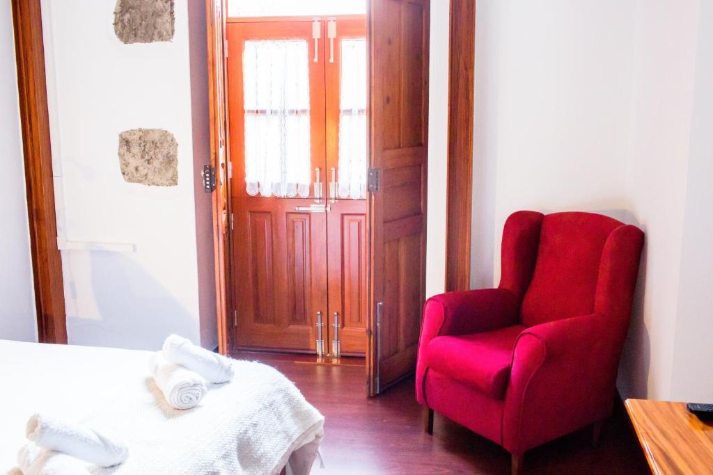sypialnia z czerwonym krzesłem i drzwiami w obiekcie Casa Rural Encarna w mieście Vega de San Mateo