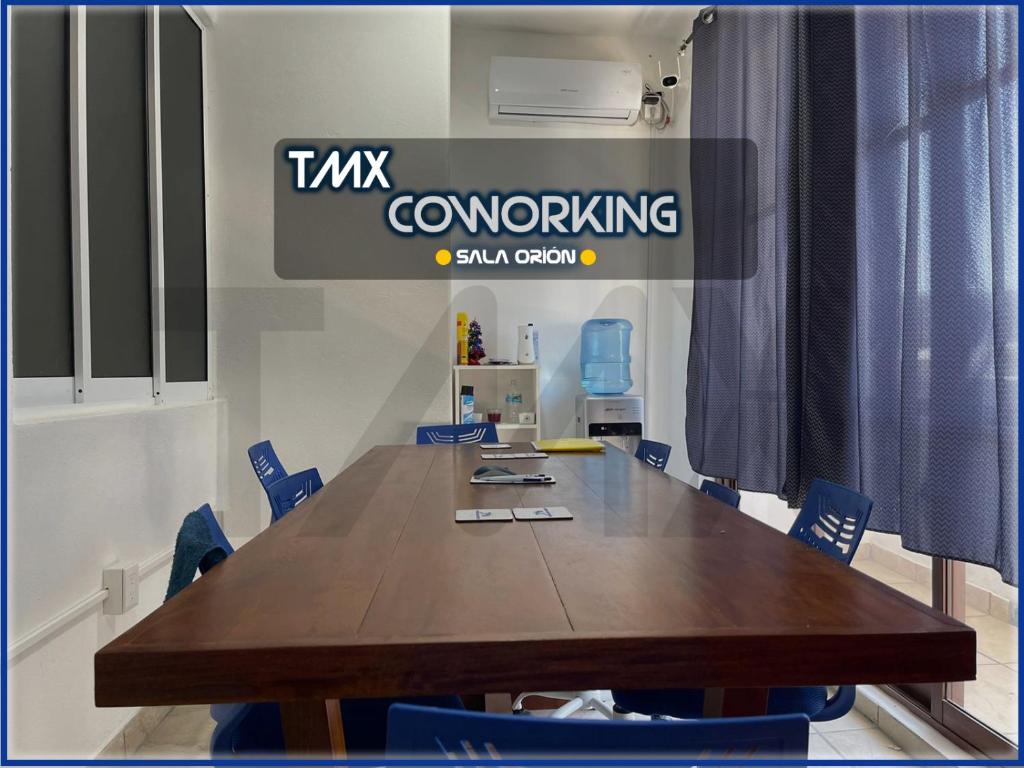 una sala conferenze con tavolo in legno e sedie blu di TMX HOSTAL a Puerto Escondido