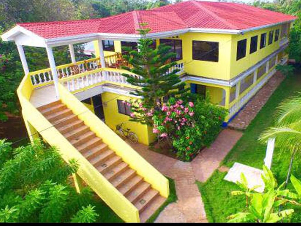 una grande casa gialla con una scala che la porta di Sunshine Hotel Little Corn Island a Little Corn Island