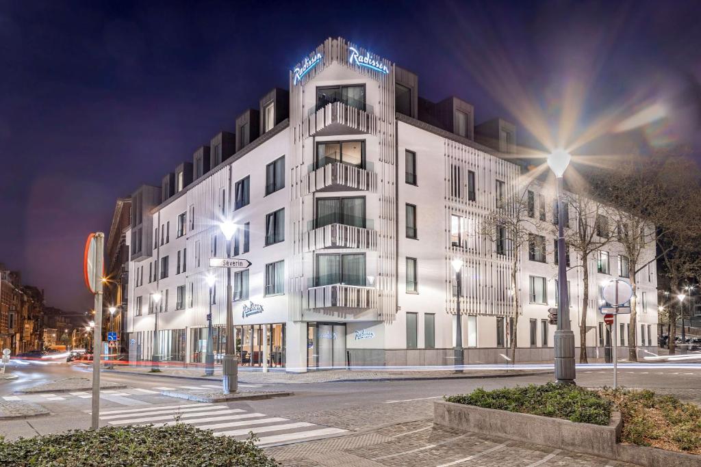 een groot wit gebouw in een stadsstraat 's nachts bij Radisson Hotel Liege City Centre in Luik