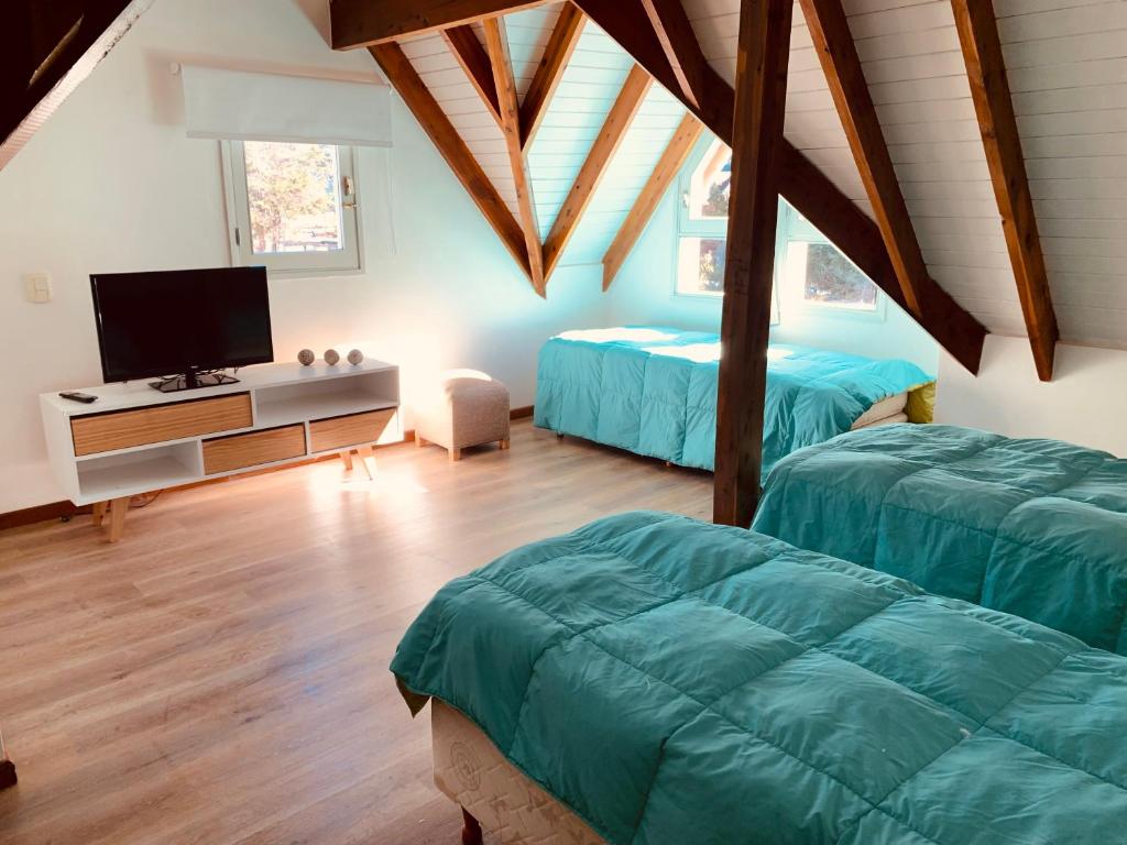 a attic bedroom with two beds and a tv at Rucalaufquen in San Martín de los Andes