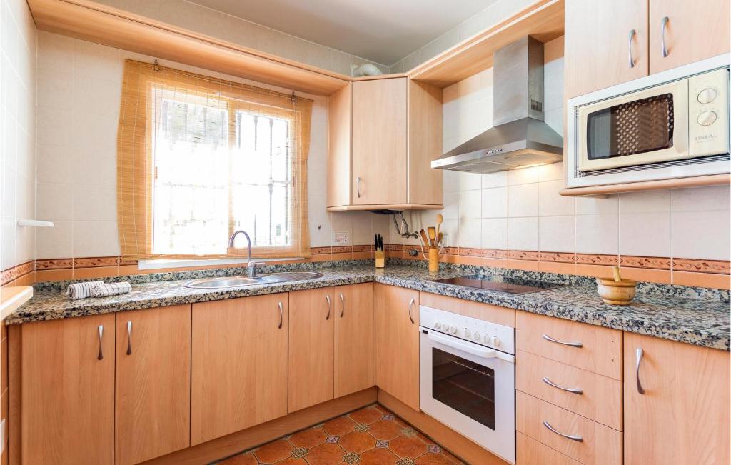 Kuchnia z drewnianymi szafkami, zlewem i kuchenką mikrofalową w obiekcie Cozy Apartment In Alcaucín With Wifi w mieście Alcaucín