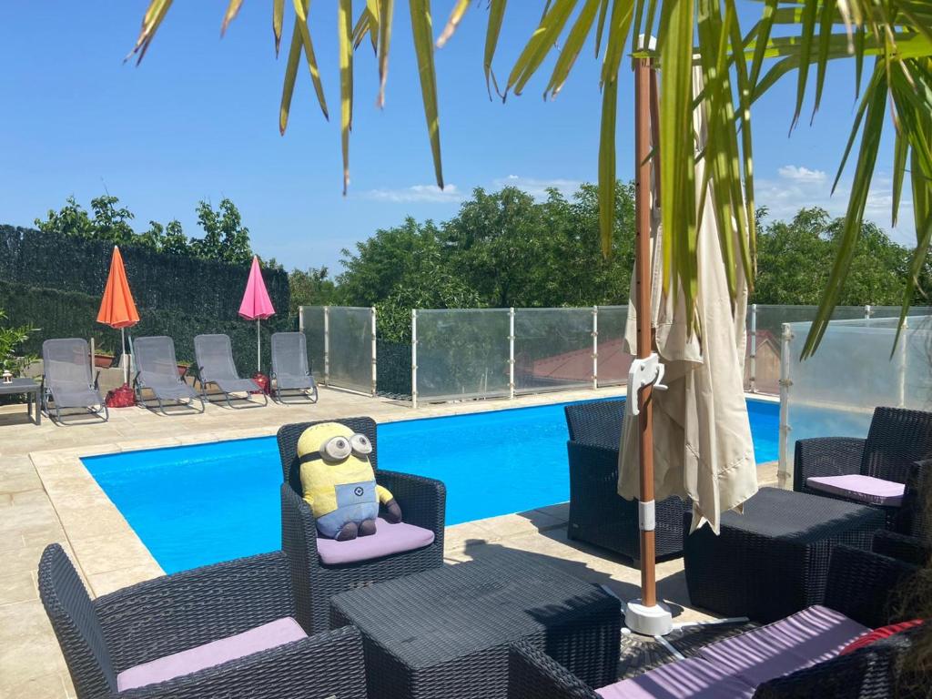 un complejo con una piscina con sillas y un personaje de dibujos animados en Magnifique Villa avec piscine Beaujolais, en Gleizé