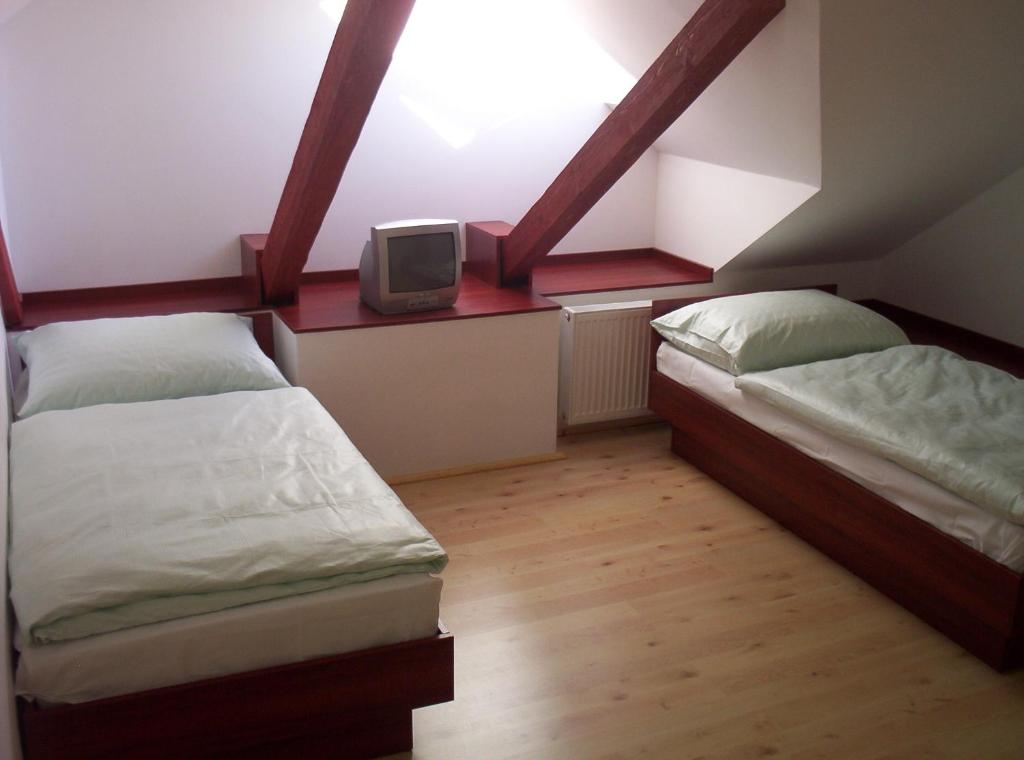 a bedroom with two beds and a tv on a shelf at Restaurant Švejk a Pension Brno in Brno