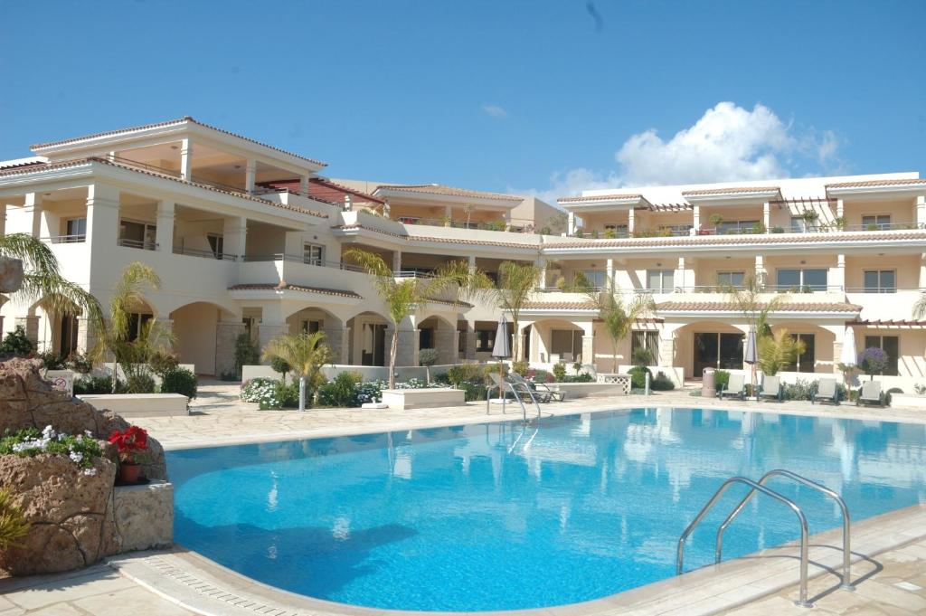 a large building with a swimming pool in front of it at Aphrodite Sands Apartment D104 in Mandria