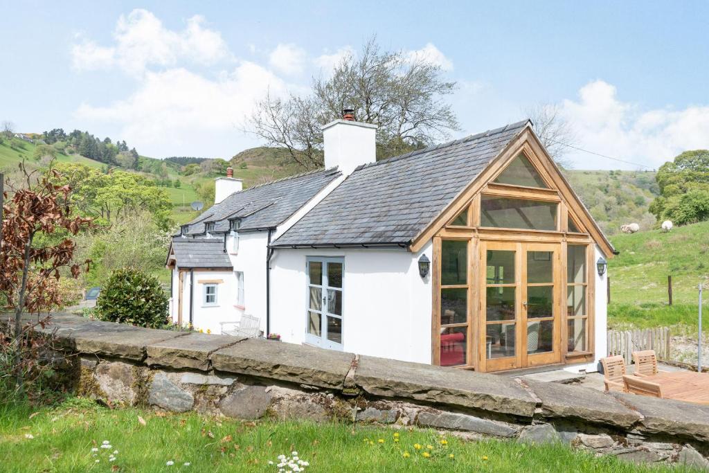 a white cottage with a conservatory in a field at Pen Y Bont in Llangollen