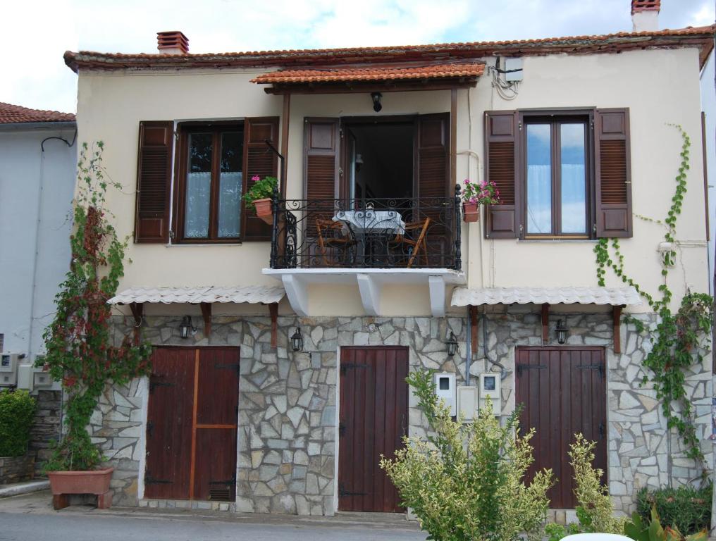 ein Haus mit einem Balkon und einem Tisch auf dem Balkon in der Unterkunft Paris & Eleni in Áfissos