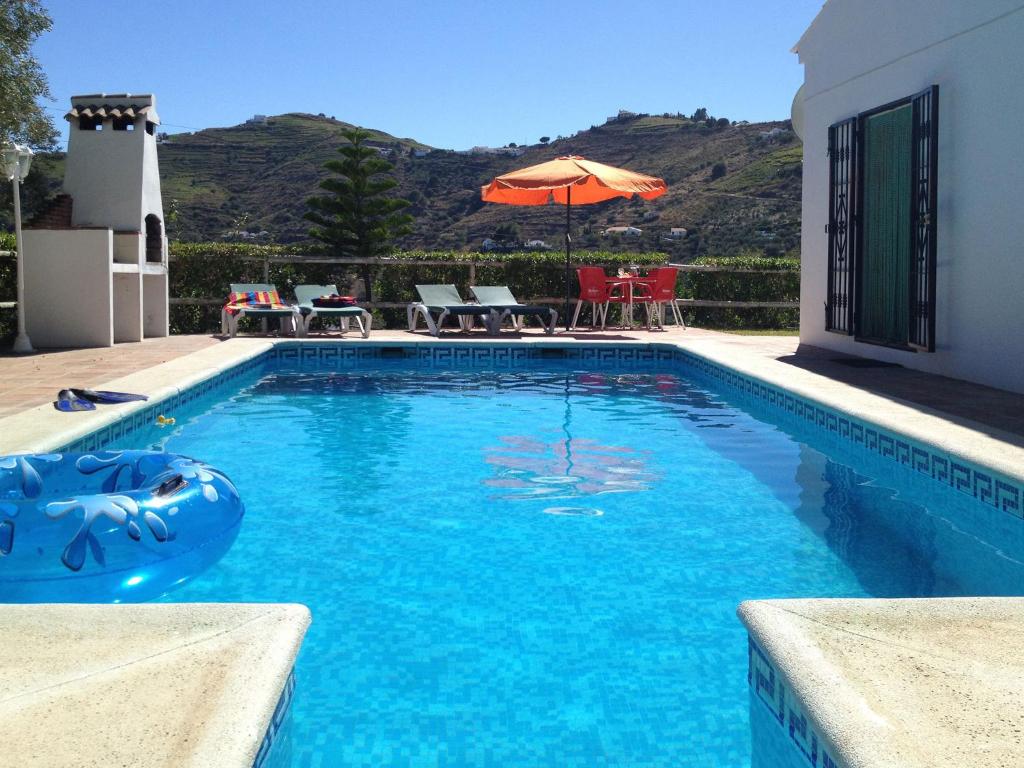 una piscina de agua azul frente a una casa en Casa Mari Carmen, en Cómpeta