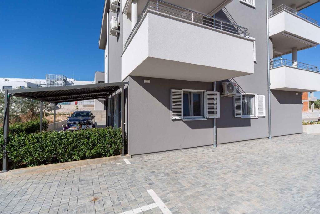 een wit gebouw met een parkeerplaats met een garage bij Apartment in Biograd na Moru - Biograd Riviera 42471 in Biograd na Moru