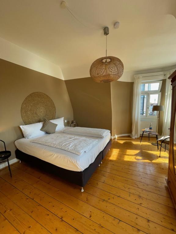 ein Schlafzimmer mit einem großen Bett und Holzboden in der Unterkunft AUERSTEIN-Hotels auerstein & auerstein-mono in Heidelberg