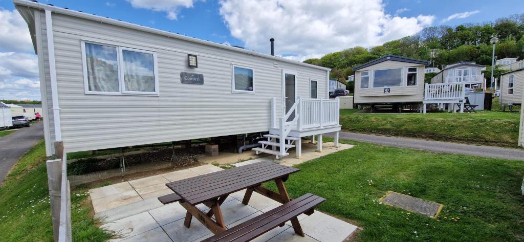 a mobile home with a picnic table and a bench at 2021 2 Bedroom Deluxe Caravan Sleeps 6 with WI-FI in Wyke Regis