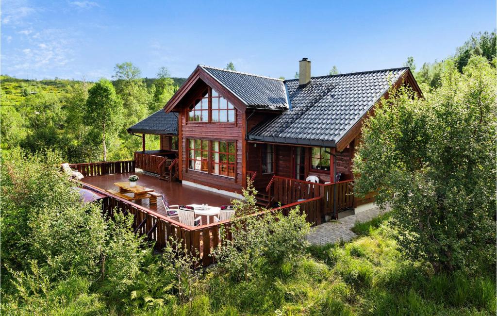 a large wooden house with a deck in a forest at Awesome Home In Norheimsund With 5 Bedrooms, Sauna And Wifi in Norheimsund