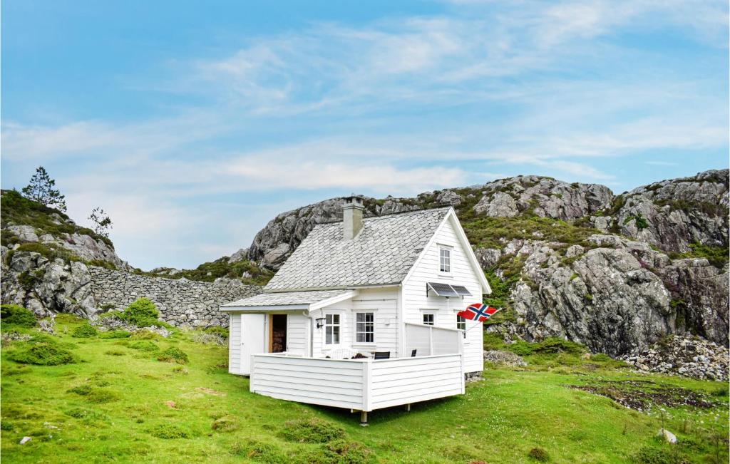 uma pequena casa branca num campo com montanhas em Lovely Home In Stolmen With House A Panoramic View em Bekkjarvik