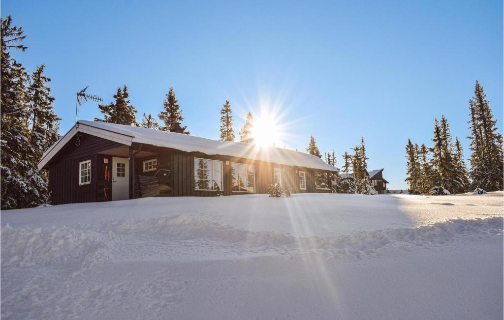 Una casa en la nieve con el sol detrás. en Lovely Home In Sjusjen With Kitchen, en Sjusjøen